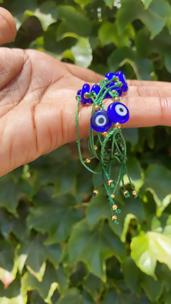 A person holding something with evil eye beads on it.