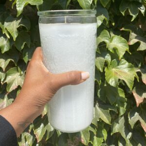 A person holding a glass of water in front of some bushes