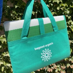 A green bag hanging on the wall of some leaves