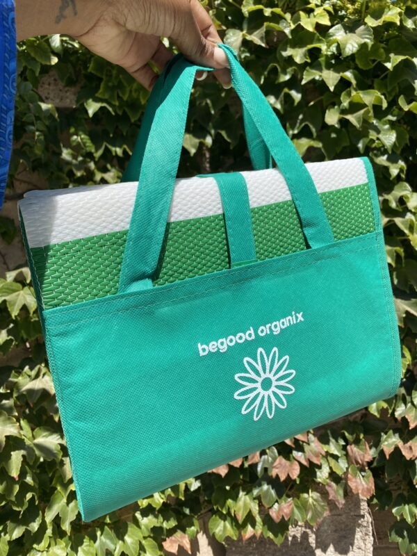 A green bag hanging on the wall of some leaves