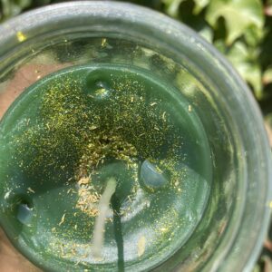 A glass of green liquid with some gold on it