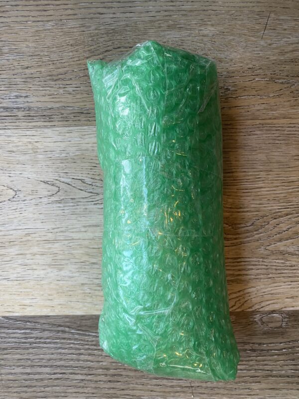 A green bubble wrap roll on top of a wooden table.