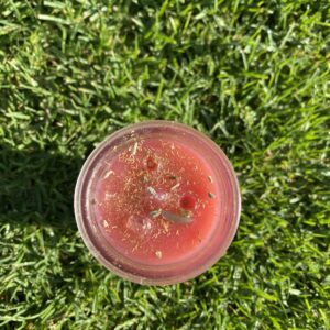 A cup of juice sitting on top of grass.