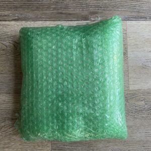 A green bubble wrap on top of a wooden table.