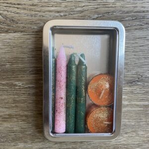 A metal box with candles and some coins inside of it