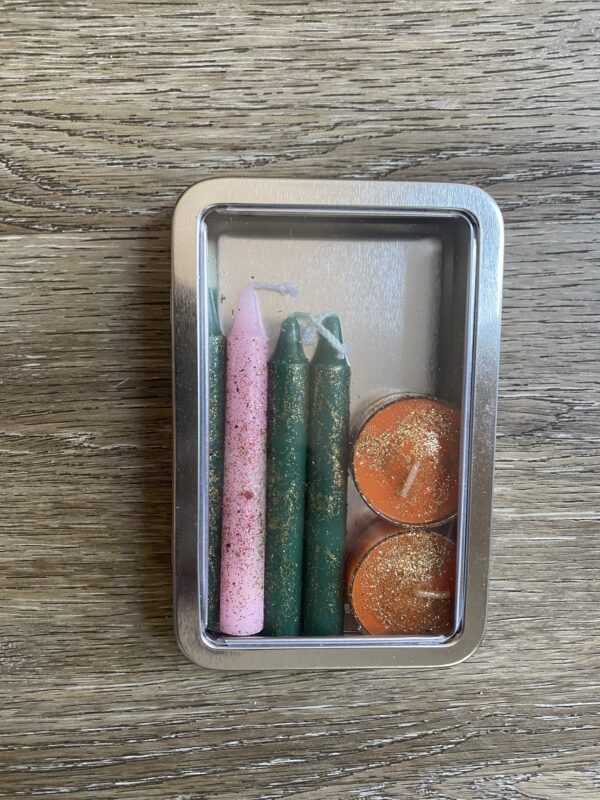 A metal box with candles and some coins inside of it