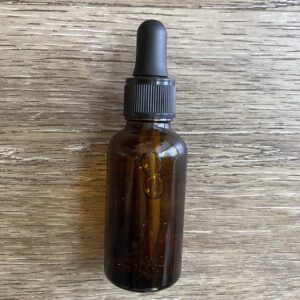 A brown bottle with black cap on top of wooden table.