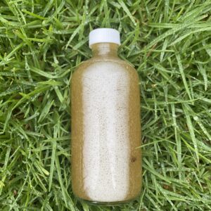 A bottle of liquid sitting in the grass.