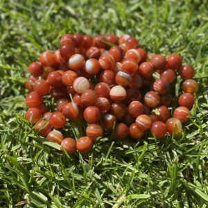 A pile of red beads sitting on top of grass.