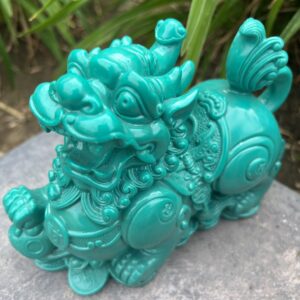 A green statue of a dragon on top of rocks.