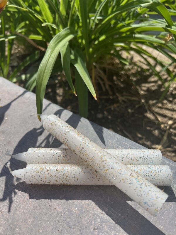 A bunch of white candles sitting on top of a table.