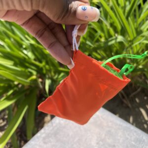 A person holding an orange bag with green string.