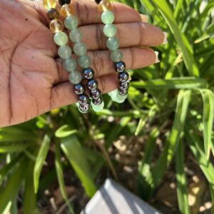 A person holding their hand out with beads in the grass.