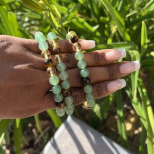 A hand holding some green beads in the grass