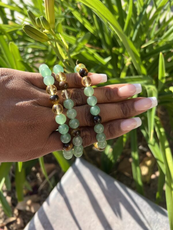 A hand holding some green beads in the grass