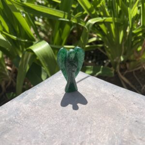 A green glass bird sitting on top of a cement surface.