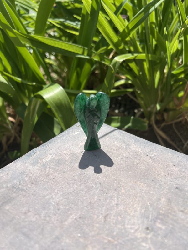 A green glass bird sitting on top of a cement surface.