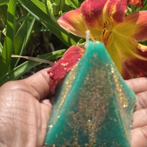 A person holding a candle in the shape of an egyptian pyramid.