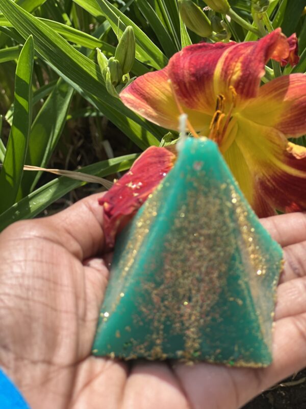 A person holding a candle in the shape of an egyptian pyramid.