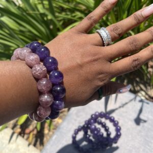 A woman 's hand is holding onto two bracelets.