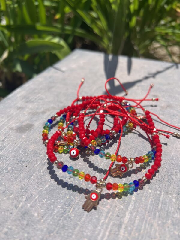 A stack of bracelets with red string and evil eye charms.