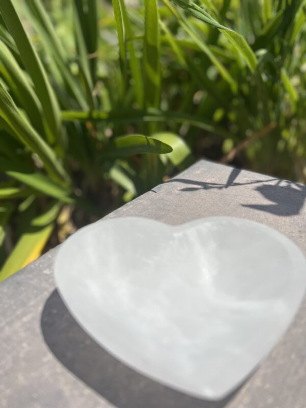 A white heart shaped bowl sitting on top of a table.