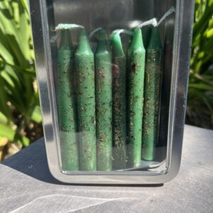 A container of green candles on the ground.