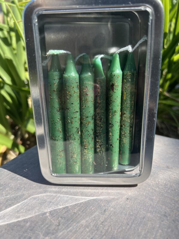 A container of green candles on the ground.