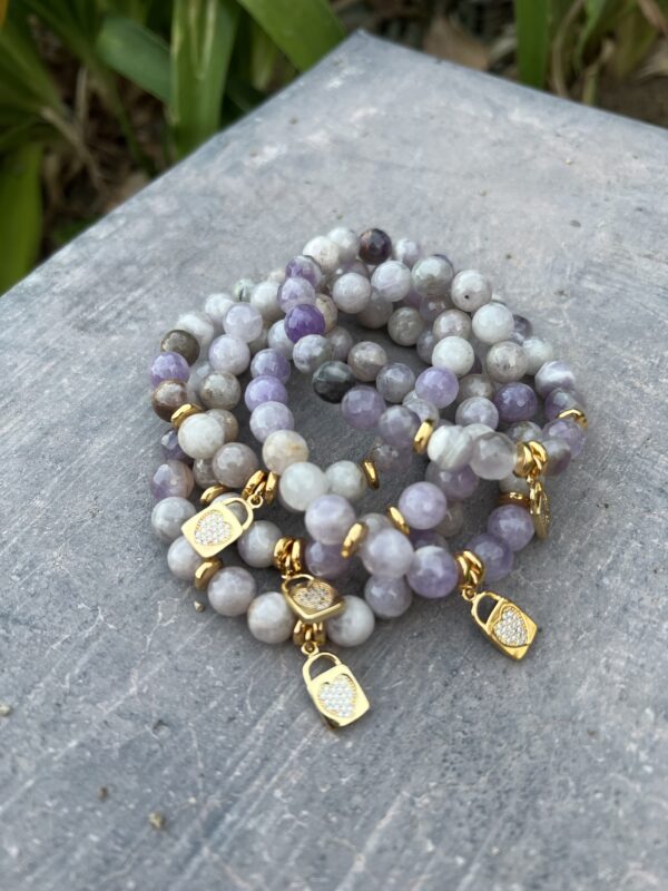 A stack of bracelets with purple and white beads.