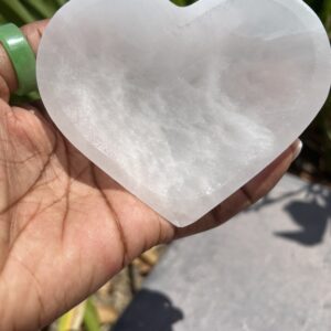 A person holding a heart shaped selenite stone.