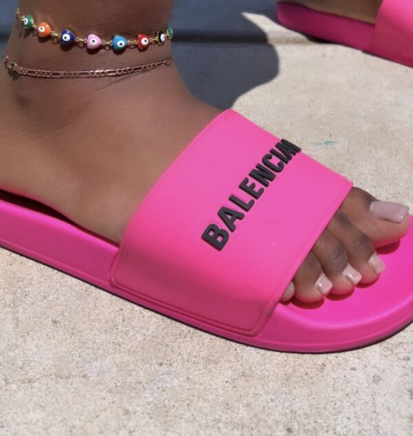 A person wearing pink sandals with the word " balenciaga " written on them.