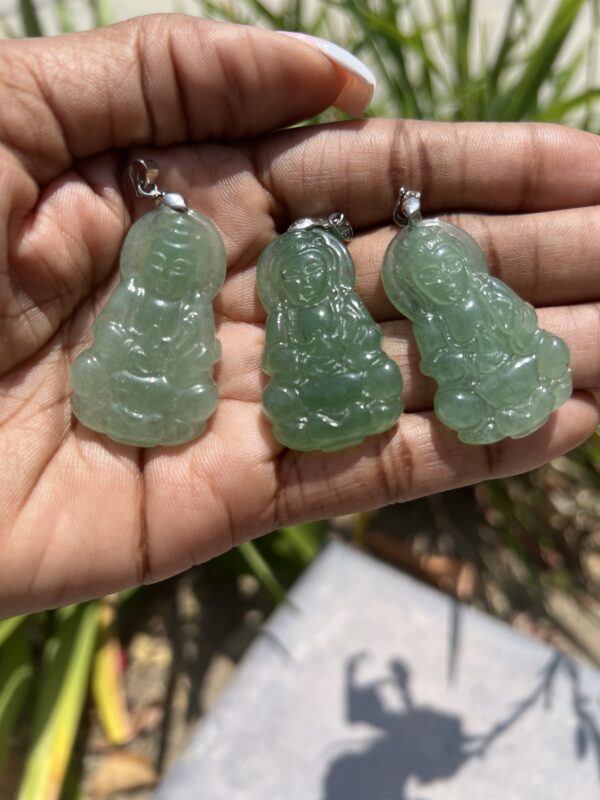 A person holding three green jade pendants in their hands.