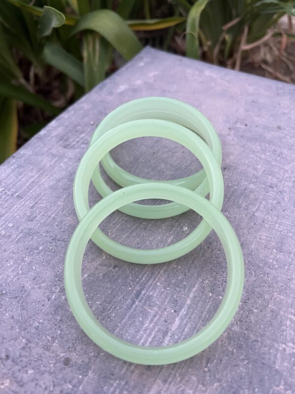 A set of four green plastic bracelets sitting on top of a table.