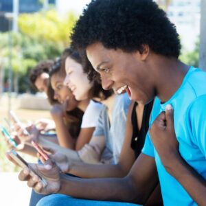 A group of people sitting on the ground looking at their phones.