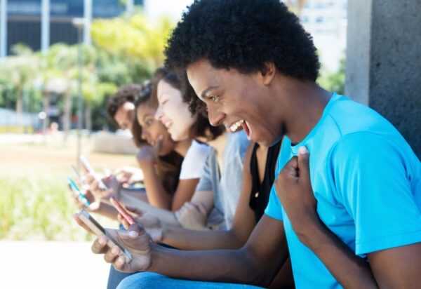 A group of people sitting on the ground looking at their phones.