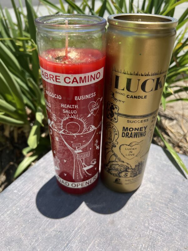 A candle and a can of luck are sitting on the ground.