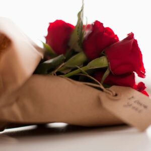 A bouquet of roses in a brown bag.