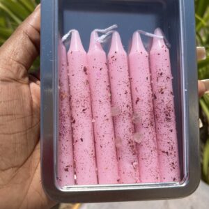 A person holding a container of pink candles.