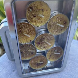 A metal container filled with candles on top of a table.