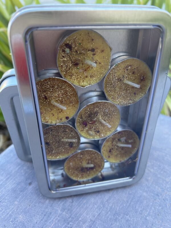 A metal container filled with candles on top of a table.