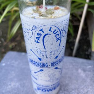 A candle in a glass with the words " fast luck " on it.