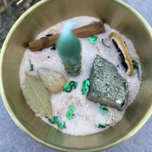 A bowl of sand with rocks and leaves in it.