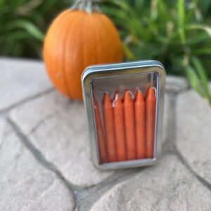 A small metal box with orange candles inside of it.