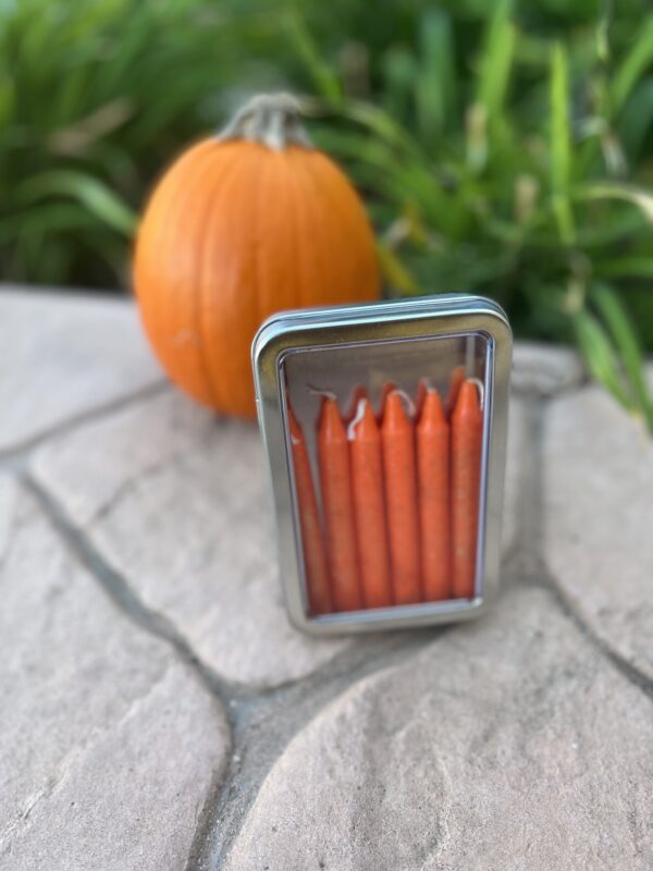 A small metal box with orange candles inside of it.