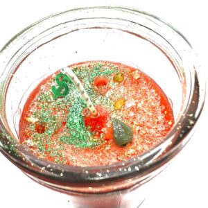 A glass of liquid with green and red sprinkles.