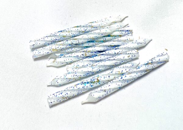 A group of white candles with blue and green speckles.