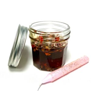 A jar of jelly next to a pink baby bottle.