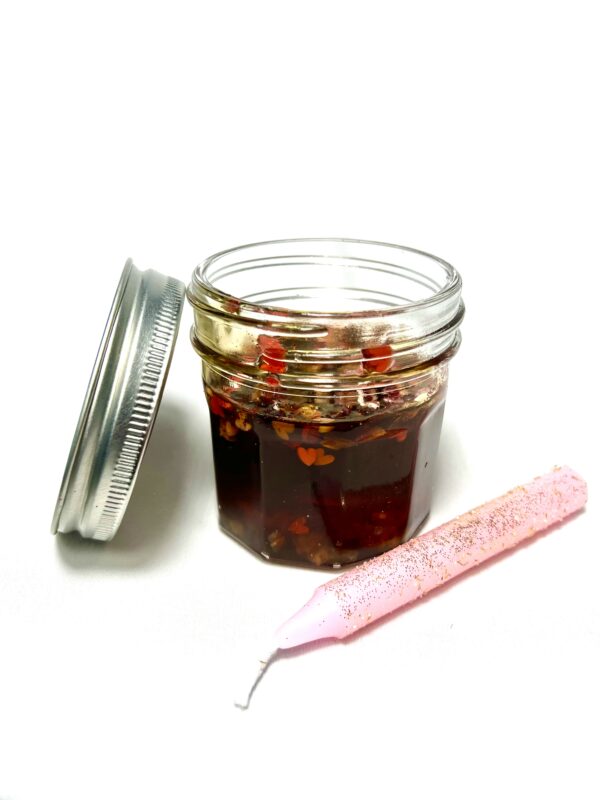 A jar of jelly next to a pink baby bottle.