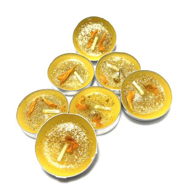 A group of eight tea lights with orange slices.