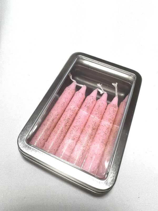 A tin of pink candles in it